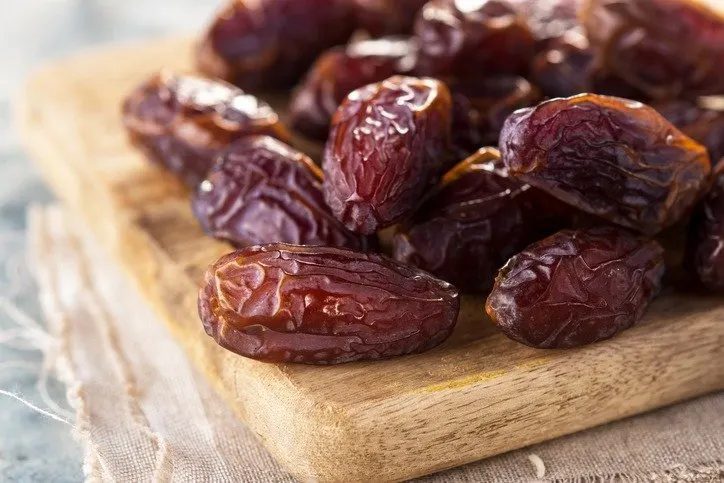 Des dattes Medjool brillantes posées sur une planche en bois